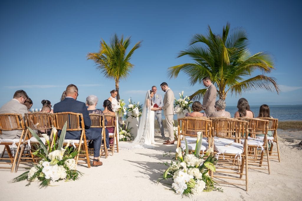 Outdoor waterfront wedding ceremony beneath palm trees