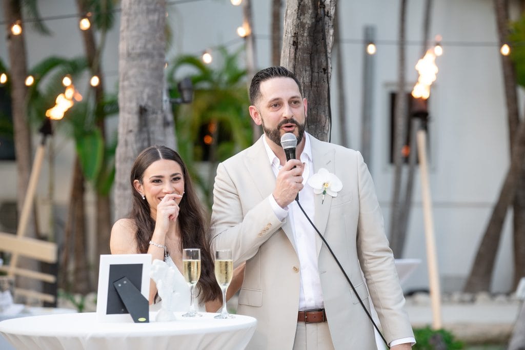 Groom giving a speech while the bride smiles during their intimate reception