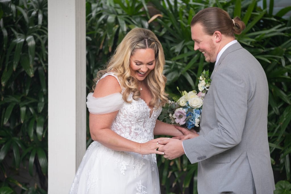 Amanda and Trevor smiling and looking down at their joined hands during their first look. 
