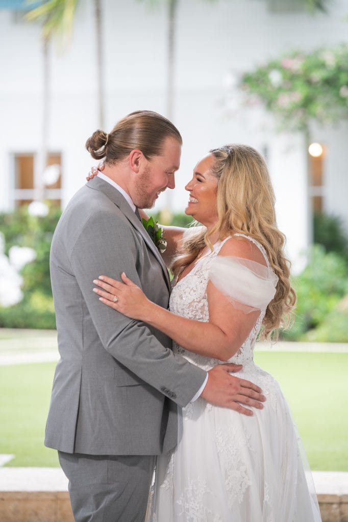 Amanda and Trevor smiling at each other while embracing on the Pelican Club's covered terrace.
