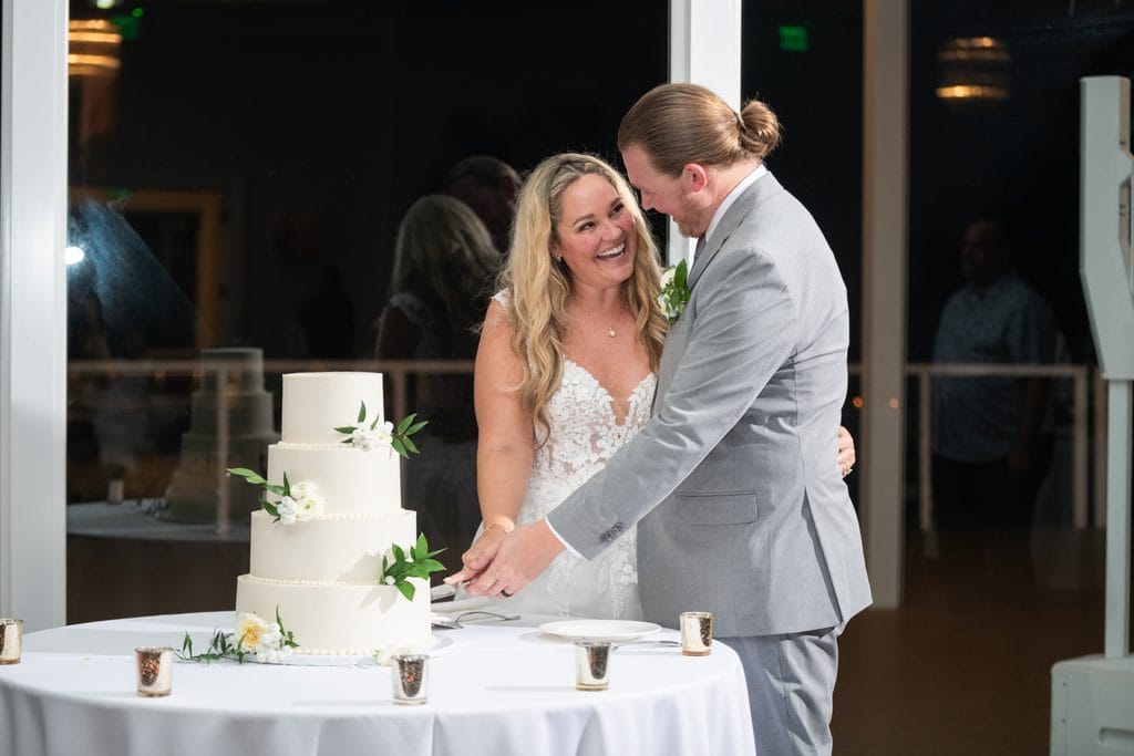 Amanda and Trevor laughing together as they cut their wedding cake.